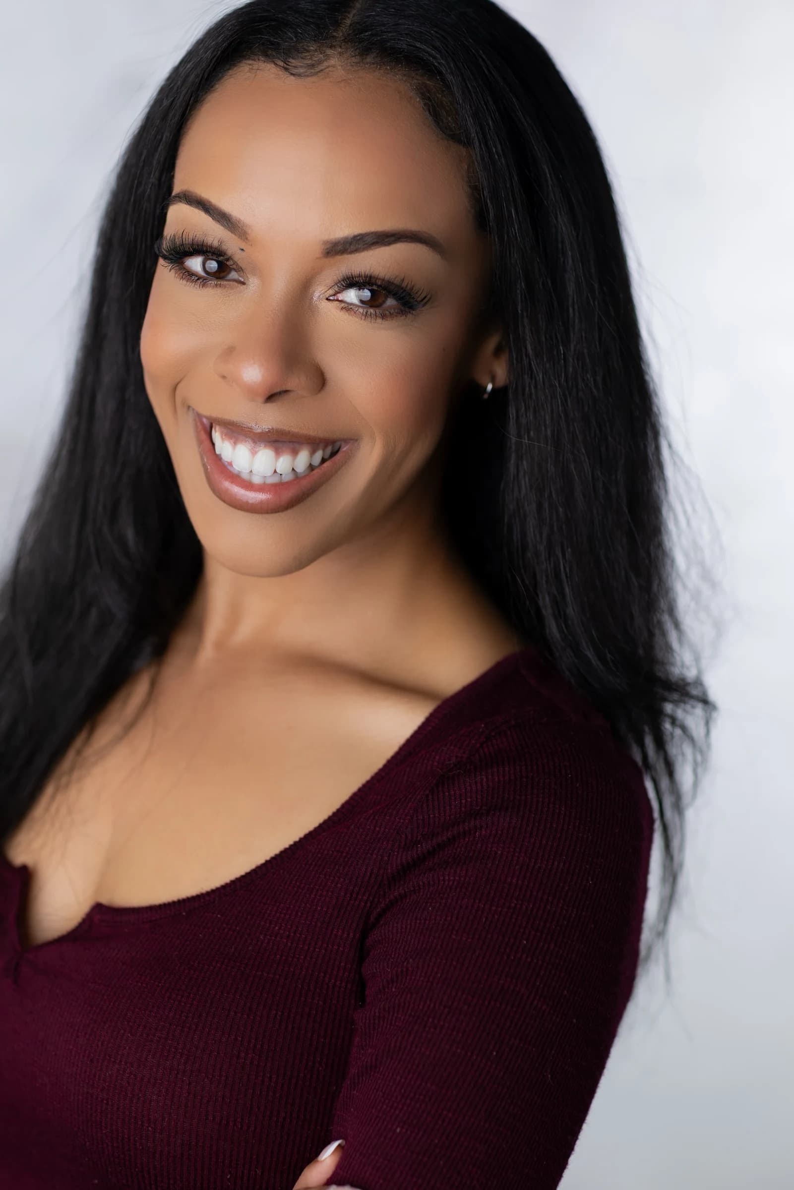 Aliyah Celeste smiling in a burgundy top against a light background.