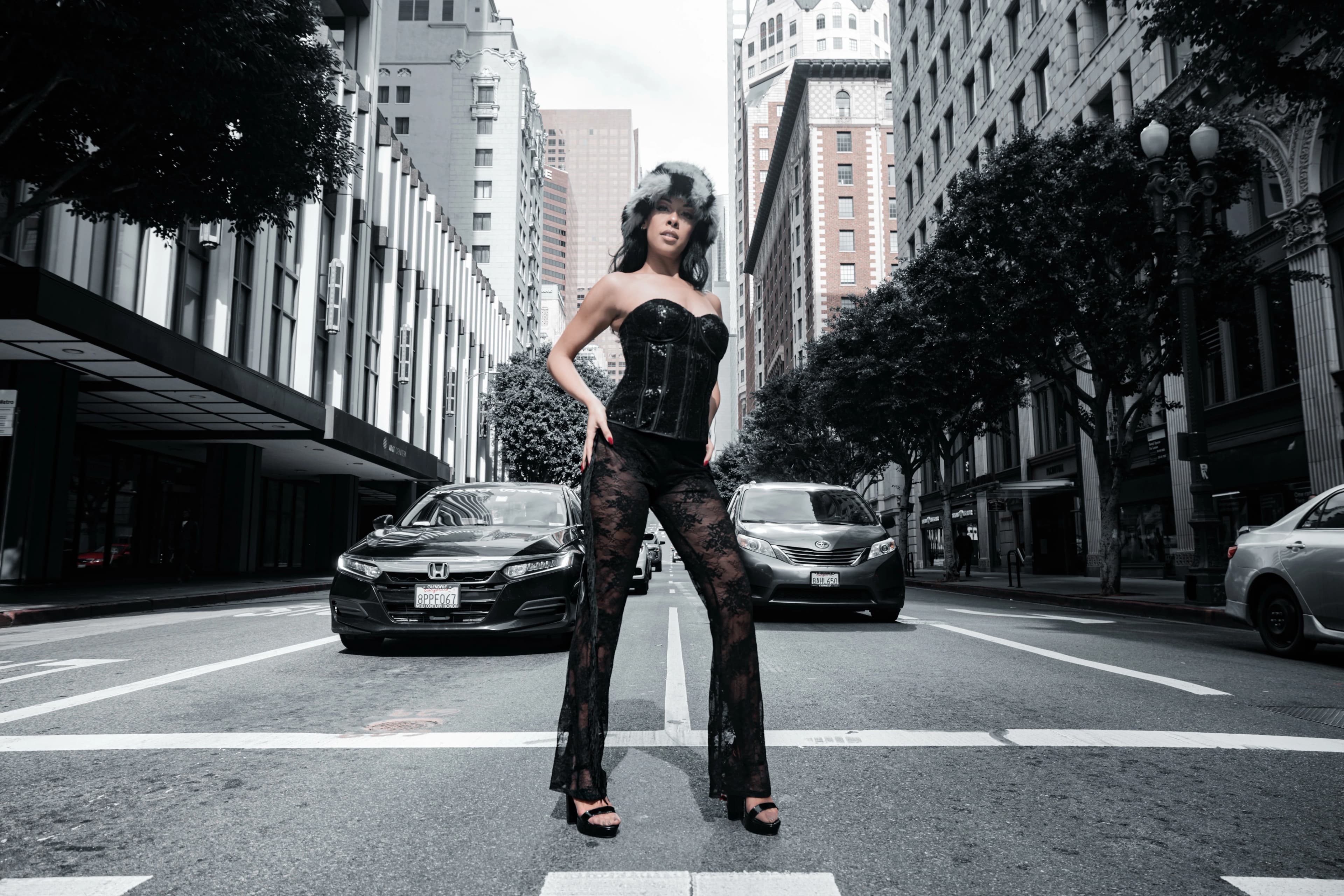 Aliyah Celeste in a black outfit and fur hat, standing on a downtown city street.